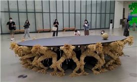 Kinetic Round Table Has 18 Headless Straw Figures Fighting for One Rolling Head
